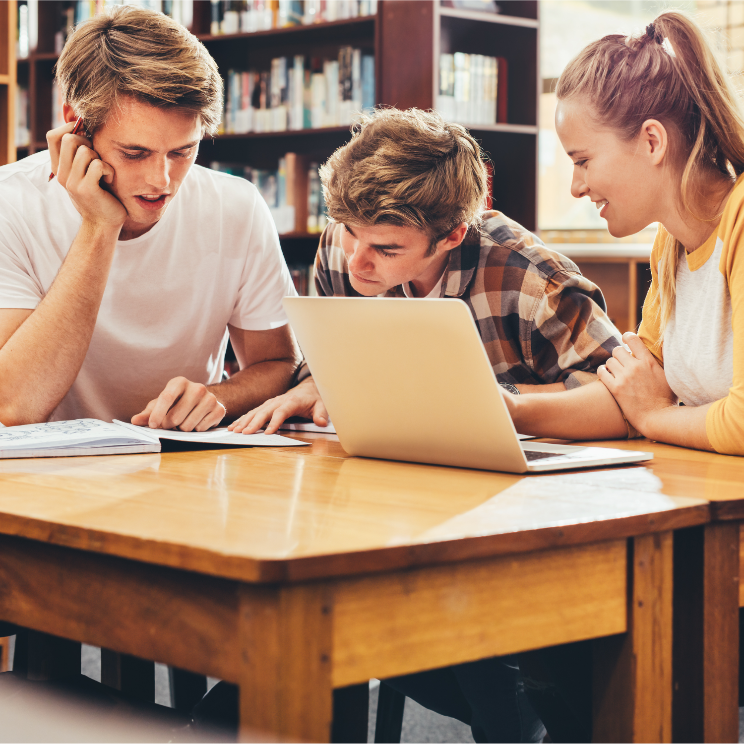 Grupa trzech studentów siedząca przy biurku
